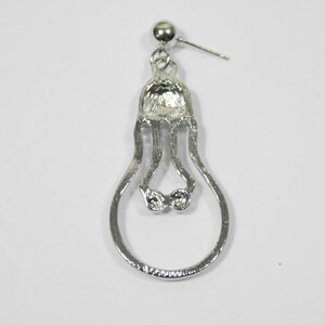 May include: Silver lightbulb shaped dangle earring with a clear rhinestone accent.