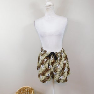 May include: A pair of brown and white patterned shorts with a black drawstring. The shorts are on a white mannequin.