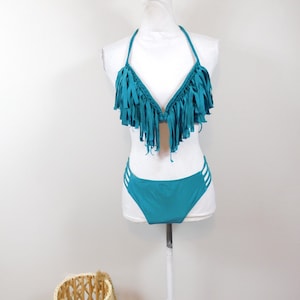 May include: Teal blue bikini with fringe detailing on the top and a high-cut bottom.