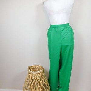 May include: A pair of green high-waisted pants on a white mannequin. The pants have a straight leg and are made of a smooth fabric.