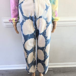 Può includere: Jeans a vita alta, gamba larga con un designo schizzato di candeggina in tonalità di blu e bianco.