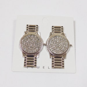 Relógio de pulso vintage prateado dos anos 2000 com mostrador de cristal de diamante e brincos de liga metálica. Bijuteria e acessório de moda.
