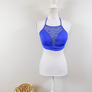 May include: A royal blue halter bikini top with a mesh panel in the front. The top is on a white mannequin.
