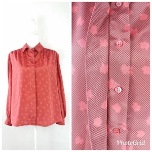 May include: A long-sleeved, red button-down shirt with a geometric pattern. The shirt has a collared neckline and a button-up front.