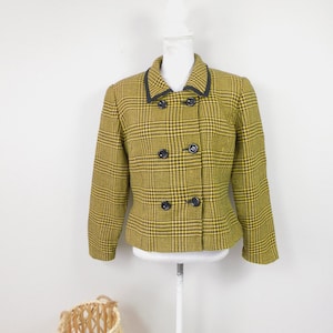 May include: A yellow and black plaid blazer with a black trim around the collar and pockets. The blazer has a double breasted closure with four black buttons.