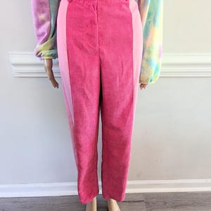 May include: Pink corduroy pants with a pink and white color block design. The pants have a high waist and a straight leg.