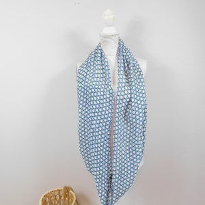 Könnte beinhalten: Ein weißer Infinity-Schal mit einem geometrischen Muster in Blau und Grün. Der Schal wird auf einer weißen Schaufensterpuppe präsentiert.