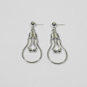 May include: A pair of silver lightbulb shaped dangle earrings. The earrings have a simple design with a small ball at the bottom of each lightbulb.