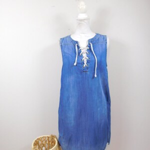 May include: A blue denim sleeveless dress with a white lace-up detail at the neckline.