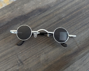 Gafas de sol estilo hippie vintage de los años 2000, negras, plateadas, con montura redonda pequeña de metal. Accesorio de moda.