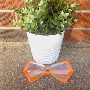 Gafas de sol vintage de los años 00 con forma geométrica de pentágono y degradado naranja, con montura de plástico retro y lentes tintadas transparentes.