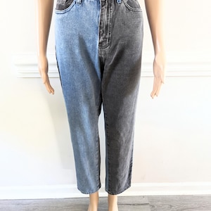 May include: A pair of high-waisted jeans with a unique design. One leg is a light blue denim, while the other leg is a dark black denim.