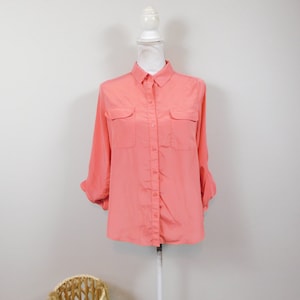 May include: A coral pink long-sleeved button-down shirt with two chest pockets.