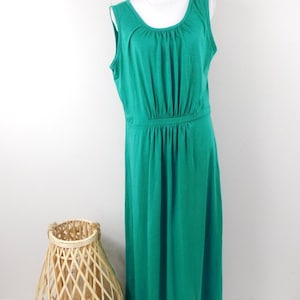 May include: A sleeveless maxi dress in a vibrant teal green color. The dress has a scoop neckline and a fitted bodice with a gathered waist.