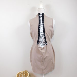 May include: A sleeveless beige dress with a lace-up back detail. The dress is on a white mannequin.