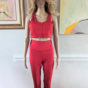 Puede incluir: Un conjunto deportivo rojo de dos piezas con un sujetador deportivo con cremallera y leggings a juego.
