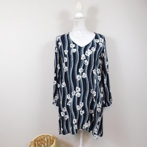 May include: A long-sleeved, navy blue dress with a white floral pattern. The dress has a V-neck and a loose fit.