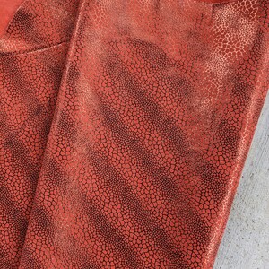 May include: Red leather with a black textured pattern. The leather has a slight sheen.