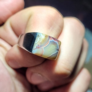 May include: A silver ring with a square-shaped agate stone. The stone has a colorful pattern of brown, white, and yellow.