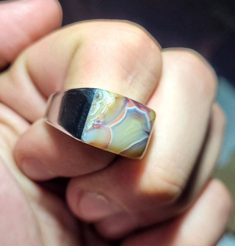 May include: A silver ring with a square-shaped agate stone. The stone has a colorful pattern of brown, white, and yellow.