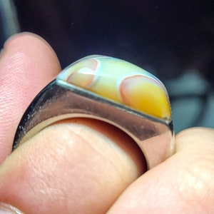May include: A silver ring with a large, rectangular, multi-colored agate stone set in the center.