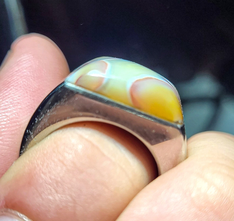 May include: A silver ring with a large, rectangular, multi-colored agate stone set in the center.