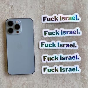 May include: A light blue smartphone next to four holographic stickers. Each sticker has the text "Fuck Israel." in a bold, sans-serif font. The stickers have a white border and a reflective, rainbow-like sheen.