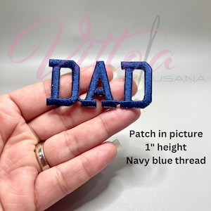 Op de afbeelding: Donkerblauwe geborduurde strijk-op patch met de tekst "DAD" in hoofdletters. De patch is 2,5 cm hoog.