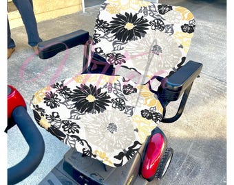 Puede incluir: Una funda de asiento con estampado floral en blanco y negro para un scooter de movilidad. La funda está hecha de una tela suave y cómoda y presenta un gran diseño floral con detalles en negro, blanco y amarillo.