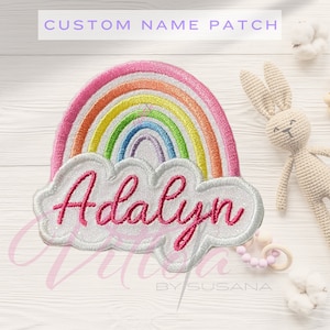 Puede incluir: Parche de arcoíris bordado con el nombre "Adalyn" en escritura rosa. El parche presenta un diseño de arcoíris colorido sobre una nube blanca. El texto en la parte superior dice "CUSTOM NAME PATCH".