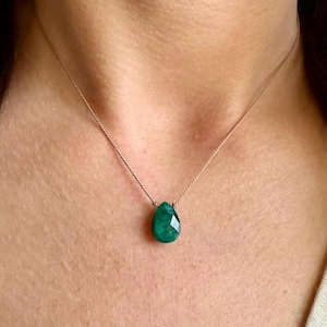 May include: A delicate necklace with a single, teardrop-shaped emerald green gemstone pendant.