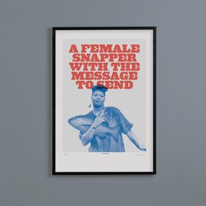 Puede incluir: Un póster enmarcado con un diseño azul y rojo. El póster presenta a una persona sosteniendo un pez y el texto "A FEMALE SNAPPER WITH THE MESSAGE TO SEND".