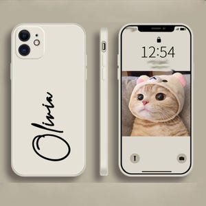 Könnte beinhalten: Cremefarbene Handyhülle mit dem Namen "Olivia" in schwarzer Schrift. Der Telefonbildschirm zeigt eine Katze mit Bärenhut und die Uhrzeit 12:54. Die Hülle wird aus verschiedenen Blickwinkeln gezeigt.