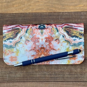 May include: A blue pen with a silver tip rests on a leather wallet with a colorful agate pattern.