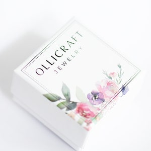 Puede incluir: Caja de joyer&iacute;a blanca con un dise&ntilde;o floral y el texto "OLLICRAFT JEWELRY" en la parte superior.
