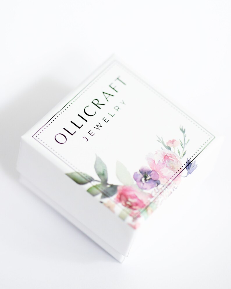 Puede incluir: Caja de joyer&iacute;a blanca con un dise&ntilde;o floral y el texto "OLLICRAFT JEWELRY" en la parte superior.