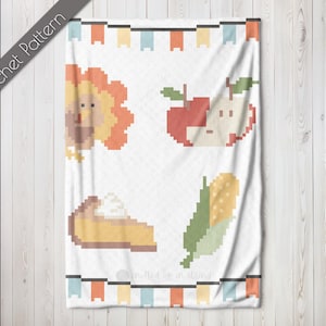 May include: White blanket with pixelated images of a turkey, apple, pie, and corn. The blanket has a banner design at the top and bottom with colorful flags. The words "Crochet Pattern" are printed diagonally on the left side.