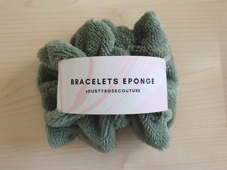 Puede incluir: Una esponja circular esponjosa de color verde con una etiqueta blanca que dice "BRACELETS EPONGE #DUSTYROSECOUTURE".