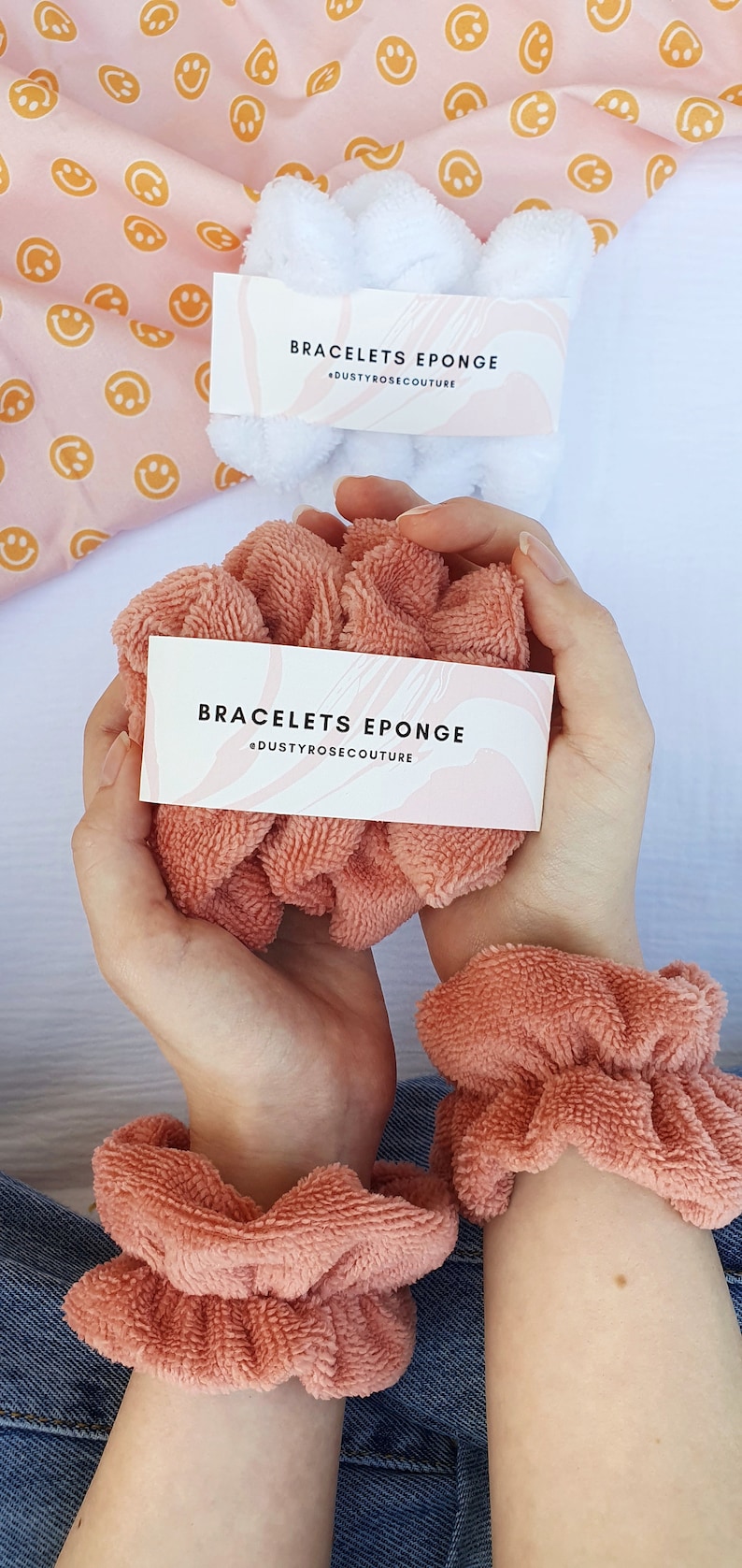 Puede incluir: Dos scrunchies de color rosa esponjoso en las mu&ntilde;ecas de una persona. Los scrunchies est&aacute;n etiquetados con "Bracelets Eponge" y "@dustyrosecouture".