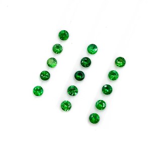 May include: A collection of thirteen small, round, faceted green gemstones arranged in three vertical columns. Each stone features a brilliant cut with multiple reflective surfaces that catch the light, displaying a vibrant, deep emerald green hue.