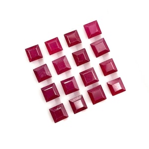 Puede incluir: Una colección de dieciséis piedras preciosas de color magenta intenso, talladas en forma cuadrada y dispuestas en una cuadrícula. Cada piedra presenta una superficie facetada con un centro puntiagudo que refleja la luz sobre las superficies.