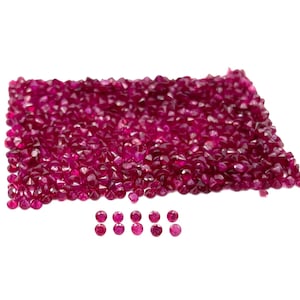 Può includere: Un grande mucchio di pietre preziose rosso rubino, con un gruppo più piccolo delle stesse pietre preziose disposte in una fila sotto.