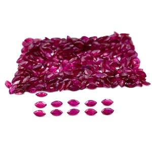 Könnte beinhalten: Ein großer Haufen loser, facettierter, marquiseförmiger Rubin-Edelsteine. Darunter befindet sich eine Reihe von 12 kleineren, facettierten, marquiseförmigen Rubin-Edelsteinen, die in einer Reihe angeordnet sind.