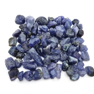Op de afbeelding: Een hoop ruwe, blauw-paarse edelstenen. De stenen zijn van verschillende groottes en vormen, sommige zijn lang en dun, terwijl andere ronder zijn.