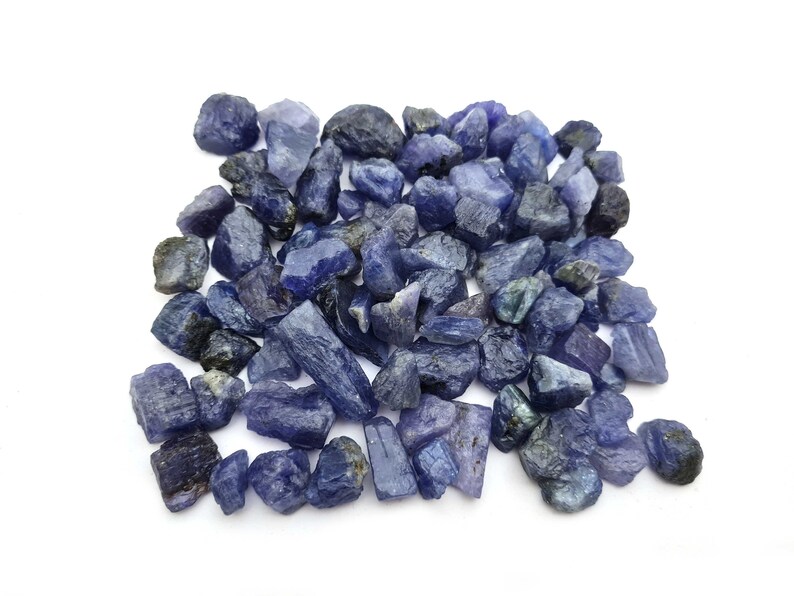 Op de afbeelding: Een hoop ruwe, blauw-paarse edelstenen. De stenen zijn van verschillende groottes en vormen, sommige zijn lang en dun, terwijl andere ronder zijn.