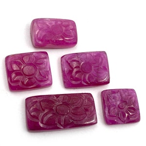 May include: Five carved pink gemstone cabochons with a floral design. The cabochons are rectangular and have a smooth, polished surface.