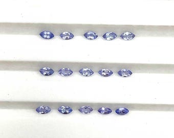 May include: Marquise-cut, light blue gemstones arranged in three rows. Each row contains five stones, displayed against a white background. The gems have a slight sparkle, suggesting they are polished.
