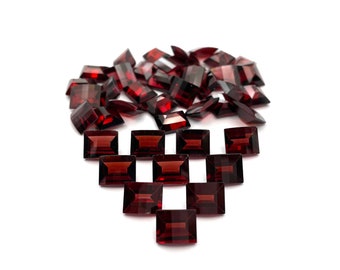 May include: A collection of dark red rectangular gemstones arranged in a heart shape on a white background.