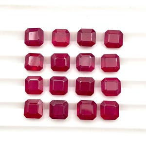 May include: Sixteen loose, square-cut rubies arranged in a four-by-four grid. Each gemstone features a deep, saturated red color with faceted surfaces that reflect light, creating a uniform appearance across the collection of individual stones.