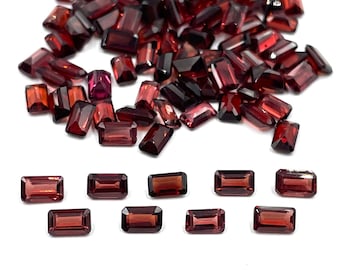 May include: A large pile of red gemstone rectangular cut loose stones.  There are 10 smaller stones laid out in a row below the pile.